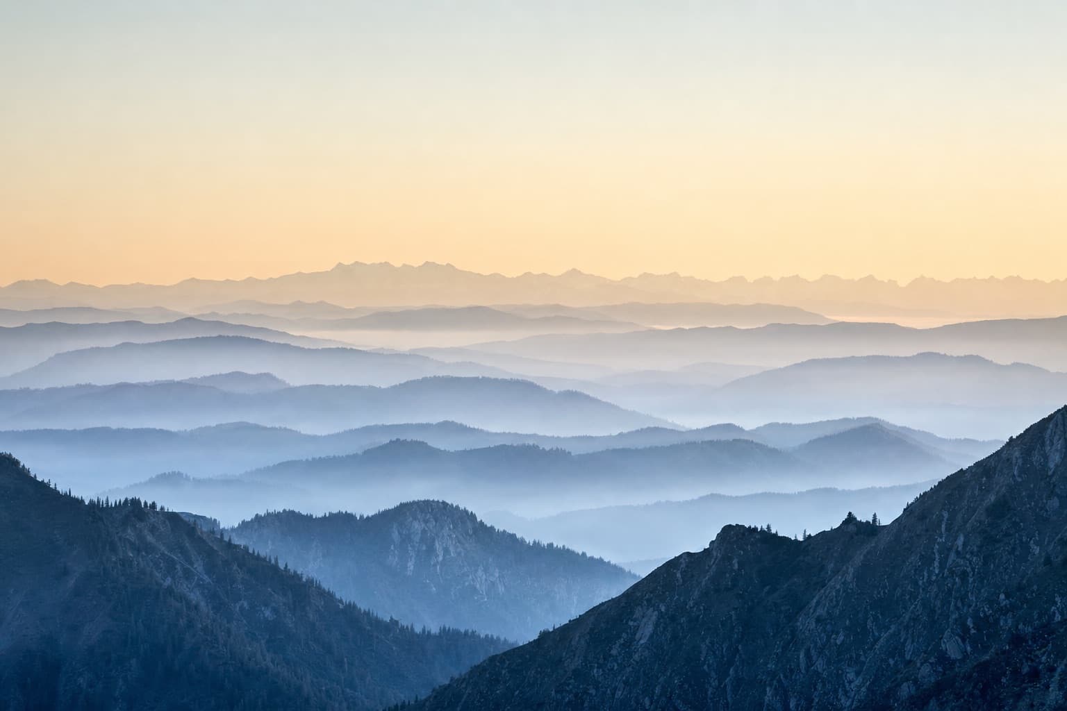 Layered mountain ridges in morning light with mist in the valleys